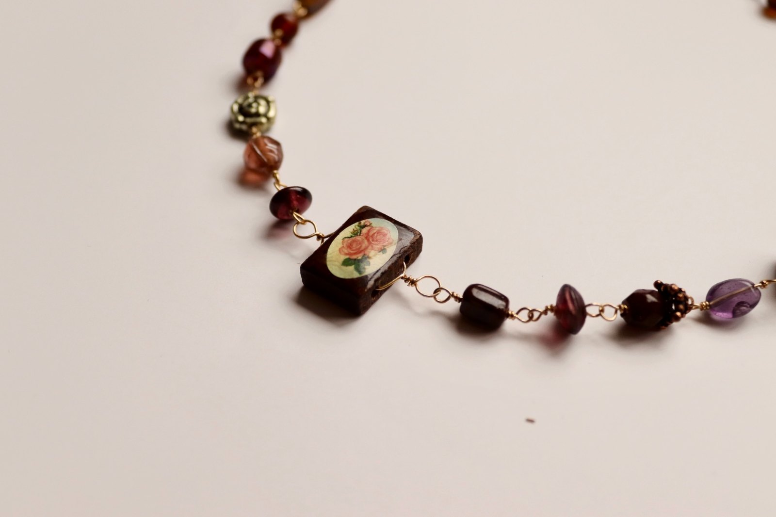 A delicate pearl-and-green-glass charm bracelet on the wrist