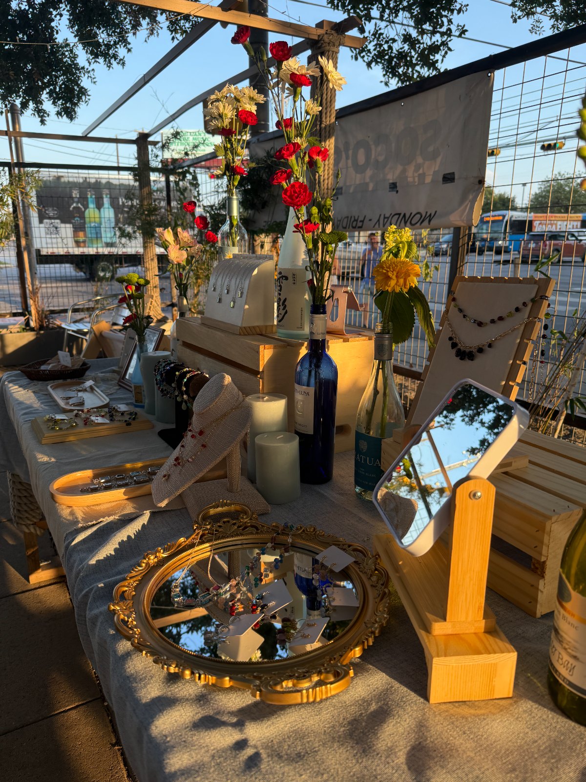 The Moya Moya booth at golden hour — jewelry displays, candles, and flowers in upcycled bottles